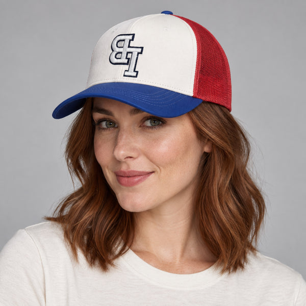 Woman wearing a Late Brake red, white and blue trucker hat with an embroidered LB monogram against a neutral studio background.
