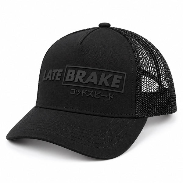 Late Brake black mesh trucker hat with a tonal LATE BRAKE wordmark on a white background.